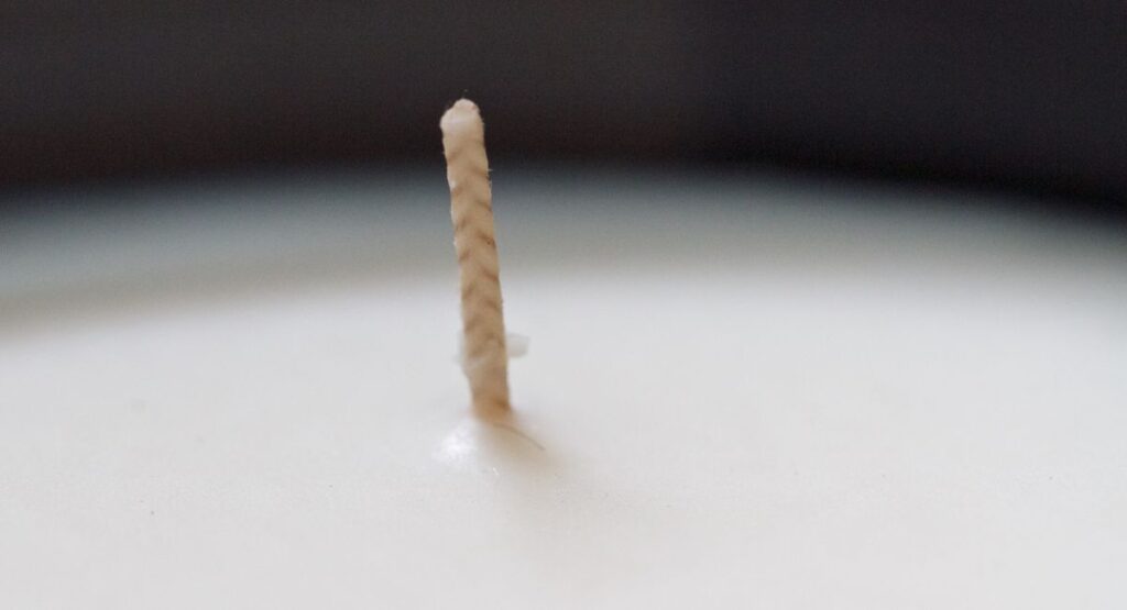 Une bougie blanche avec une mèche en coton
